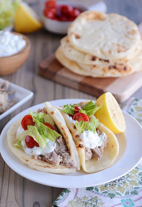 Two pork tacos on flatbread on a white plate.