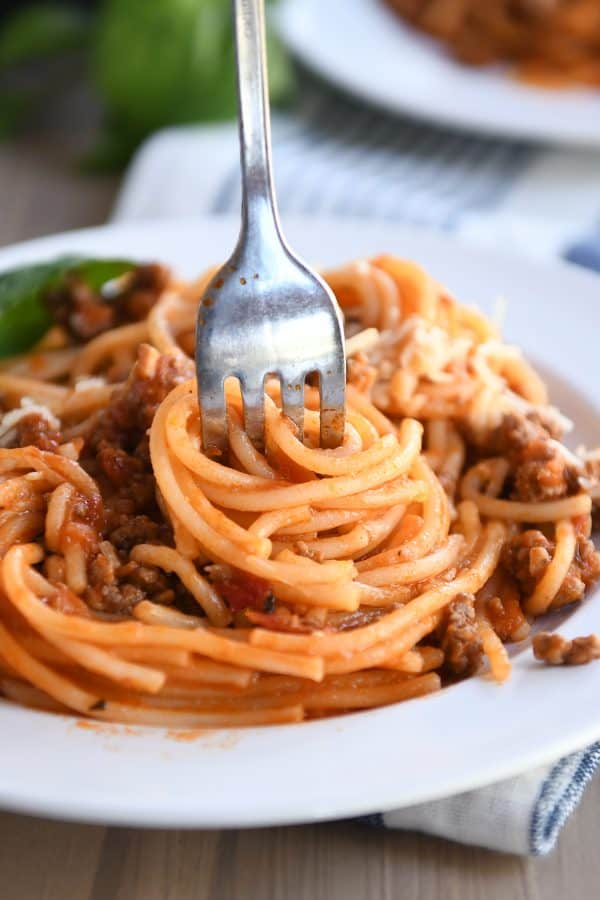 Instant pot spaghetti twisted around fork on white plate.