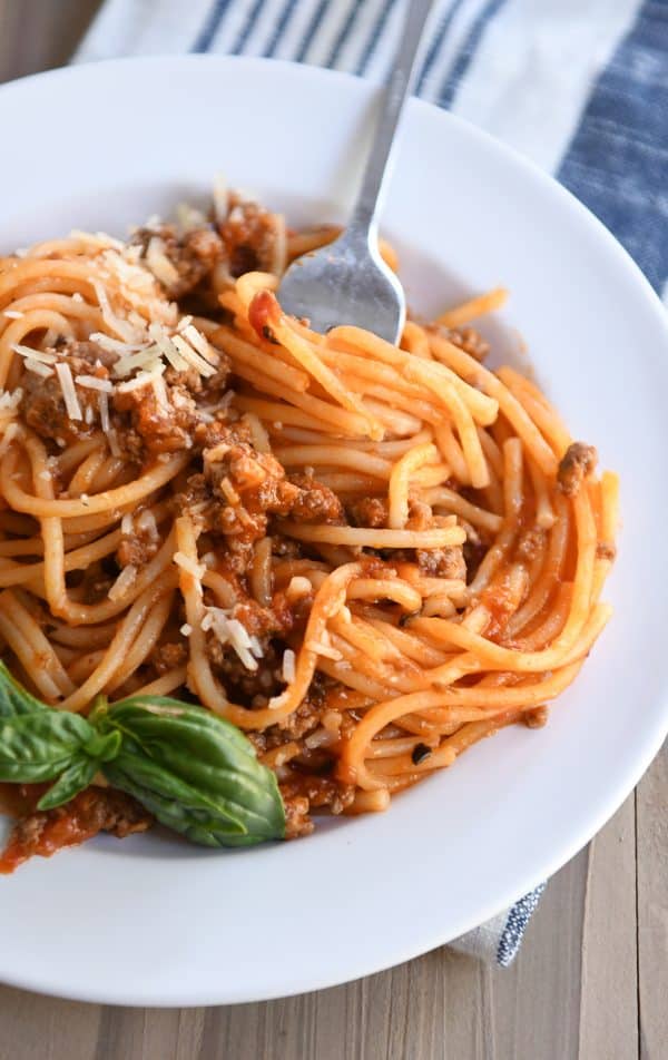 Instant pot spaghetti twisted around fork on white plate.