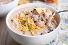 Instant Pot white chicken chili in white bowl with spoon and shredded cheese.