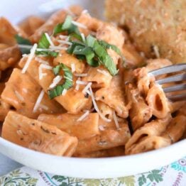 White bowl with Instant Pot creamy baked ziti and piece of focaccia bread.