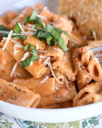 White bowl with Instant Pot creamy baked ziti and piece of focaccia bread.