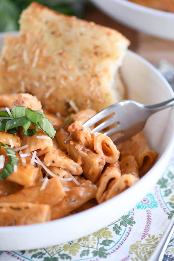 White bowl with Instant Pot creamy baked ziti and piece of focaccia bread.