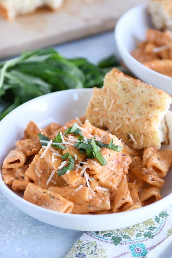 White bowl with Instant Pot creamy baked ziti and piece of focaccia bread.