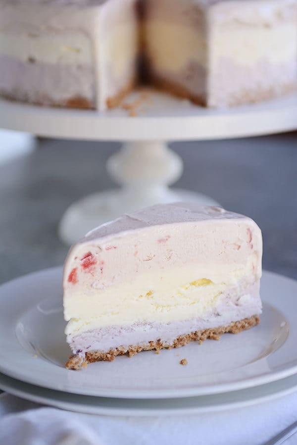 A slice of layered ice cream cake with a sugar cone crust on a white plate.