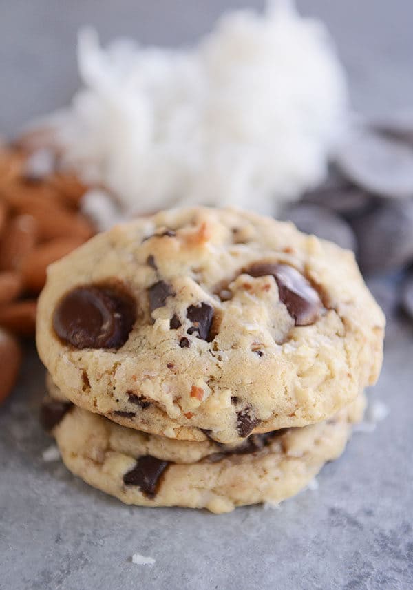 Two chocolate chunk, almond, coconut cookies stacked on top of each other.