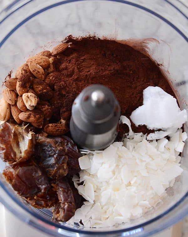 A food processor full of ingredients to make dark chocolate almond joy bites. 