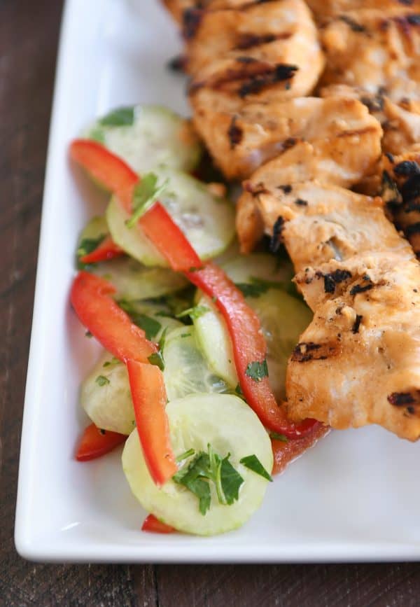 Cucumber salad with almond coconut milk chicken satay on white platter. 