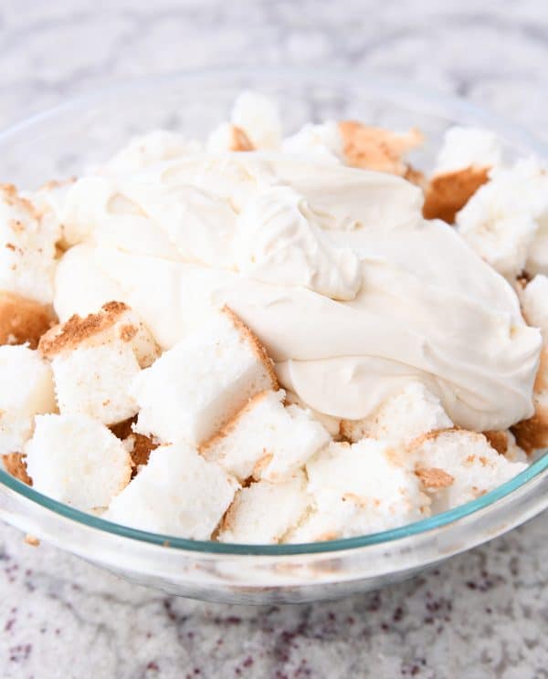Bowl of angel food cake pieces and cream poured on top.