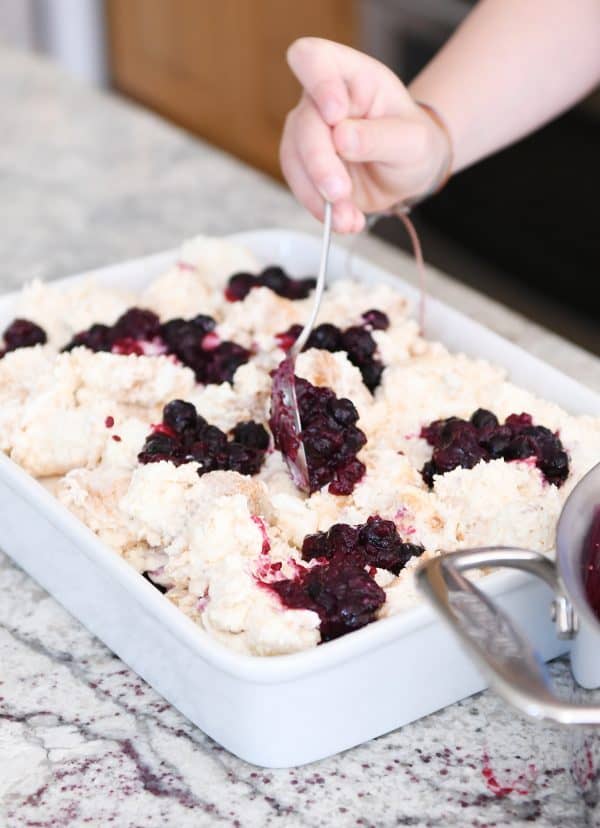 Spooning the blueberry filling on top of the creamy angel food cake pieces.