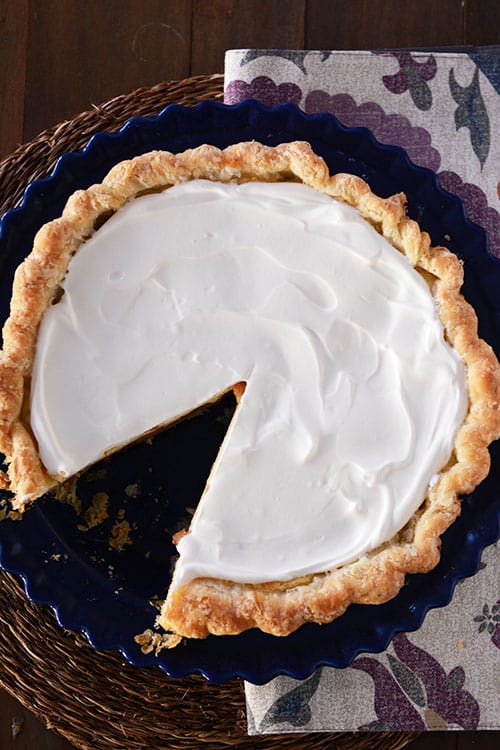 Top view of a whipped cream topped pie with a slice cut out.