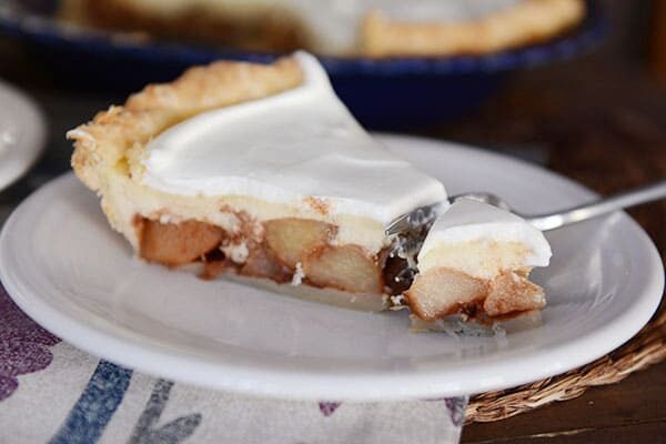 A slice of apple cheesecake pie with a bite being taken out. 