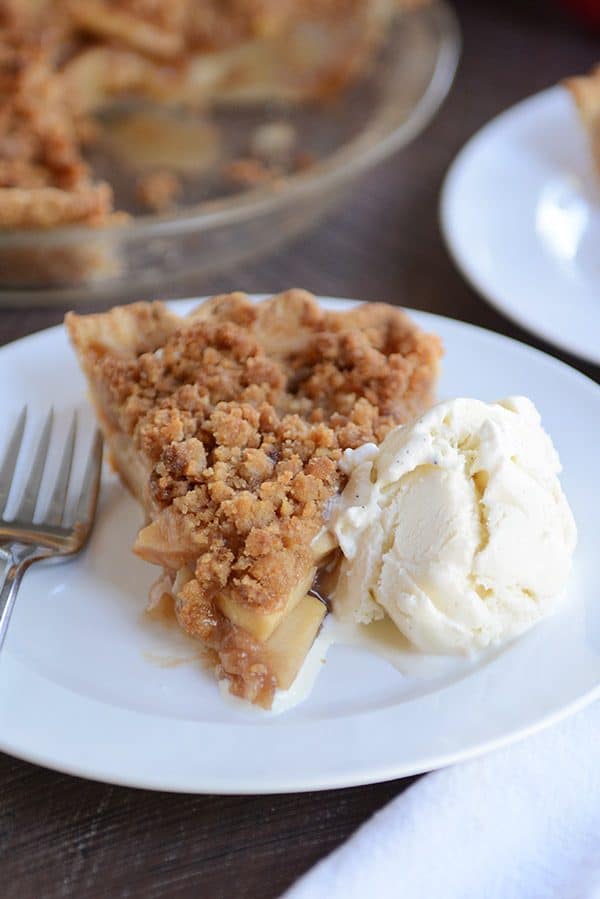 A slice of apple crumble pie with a scoop of vanilla ice cream on the side.