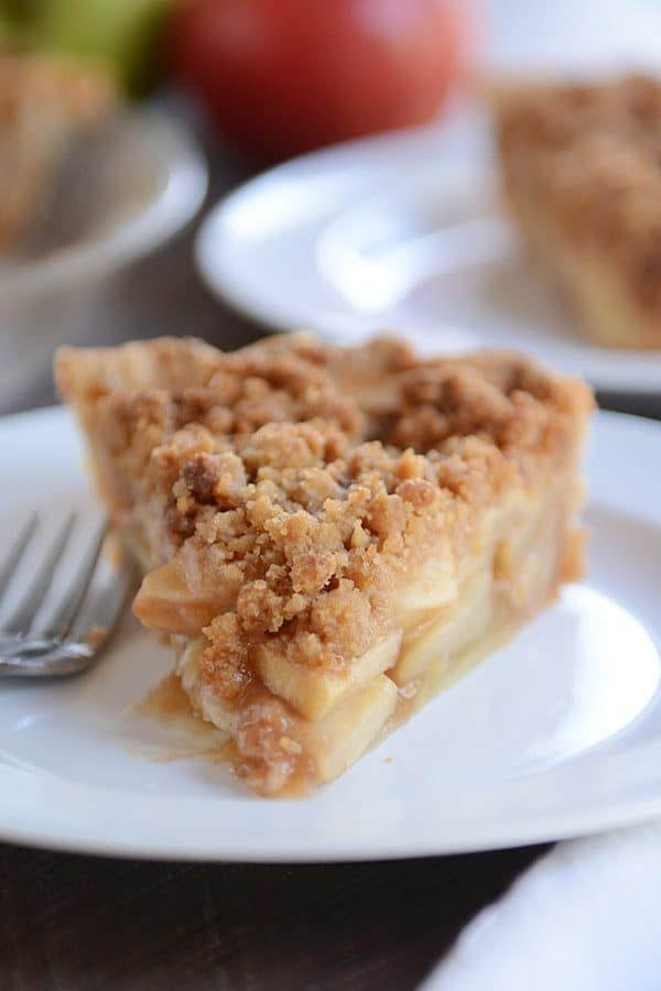 A piece of apple crumble pie on a white plate.
