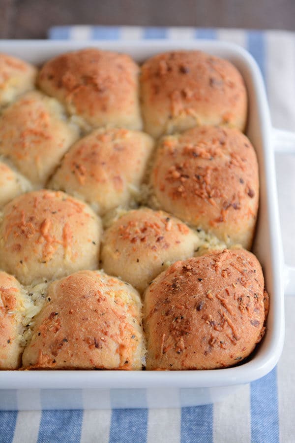 A white pan of golden brown cooked asiago topped rolls. 