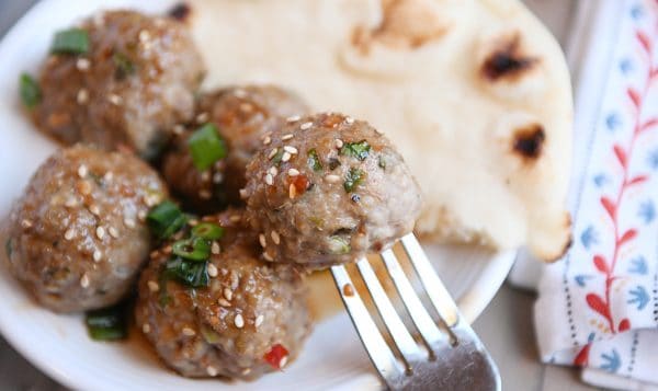 Asian meatball on fork with piece of naan in background.