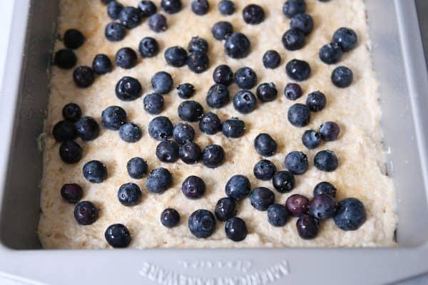 Unbaked pan of fluffy baked pancake batter with fresh blueberries on top.