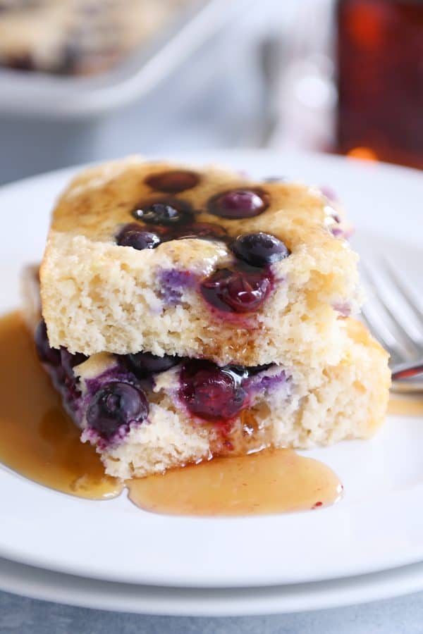 Syrup on top of stack of squares of fluffy baked pancakes.