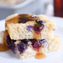 Drizzling syrup on stack of fluffy baked pancakes.