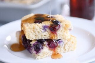 Drizzling syrup on stack of fluffy baked pancakes.