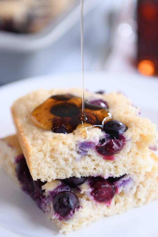 Drizzling syrup on stack of fluffy baked pancakes.