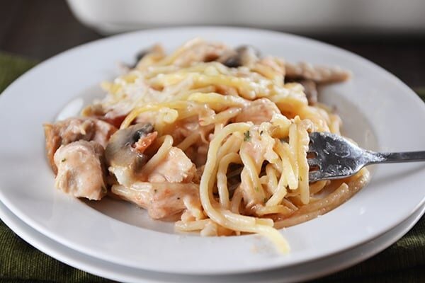 A white plate with creamy spaghetti, chicken, and mushrooms.