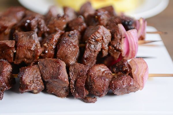 a white tray of cooked balsamic beef kebabs 