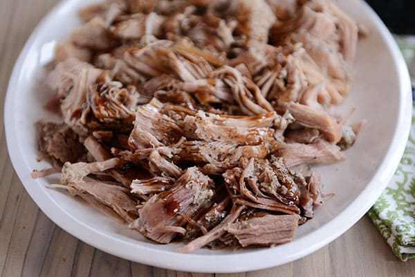 A plate full of shredded pork with balsamic glaze drizzled over the top