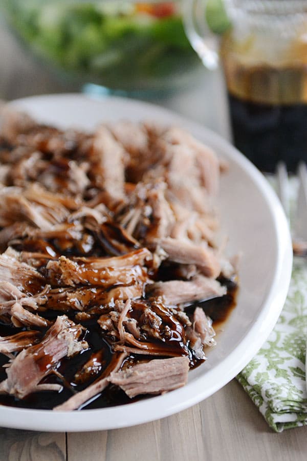 A plate full of shredded pork with balsamic glaze drizzled over the top