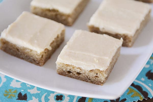 A white platter with iced banana bars. 