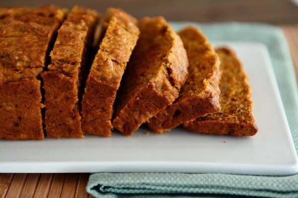 A white platter with a side view of a loaf of sliced banana carrot bread. 