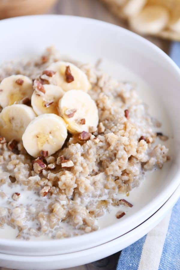 Close up of white bowl filled with Instant Pot banana bread steel cut oats with sliced bananas and milk.