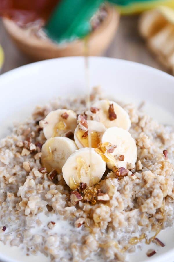 Honey being drizzled over bowl of Instant Pot banana bread steel cut oats.