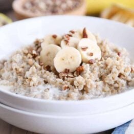 White bowl filled with Instant Pot banana bread steel cut oats with sliced bananas and milk.