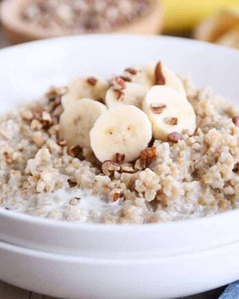 White bowl filled with Instant Pot banana bread steel cut oats with sliced bananas and milk.