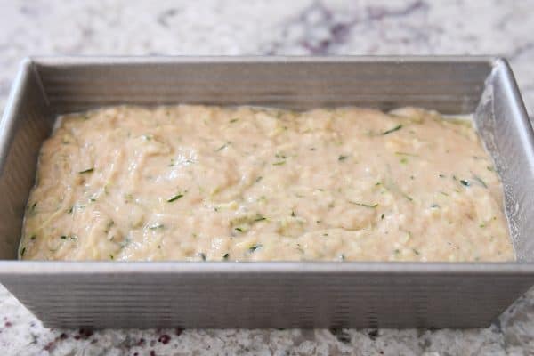 Metal loaf pan filled with unbaked zucchini banana bread batter.