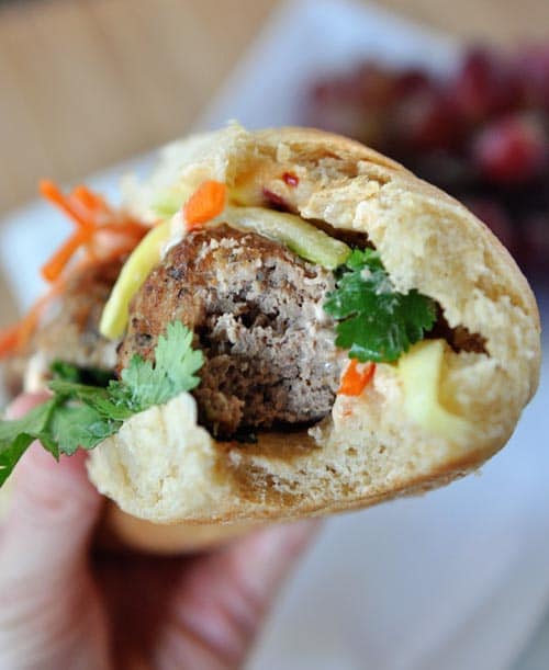 Front view of a banh mi meatball sub sandwich with a bite taken out. 