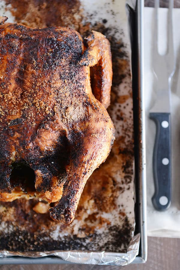 Top view of a roasted whole chicken on a tinfoil lined cookie sheet.