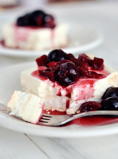 A piece of meringue dessert with berries on top with a fork taking a bite out.