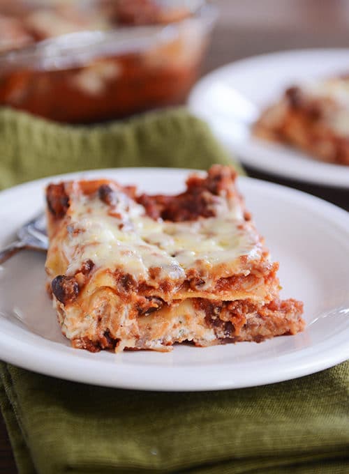 A square of cheesy black bean lasagna on a white plate. 