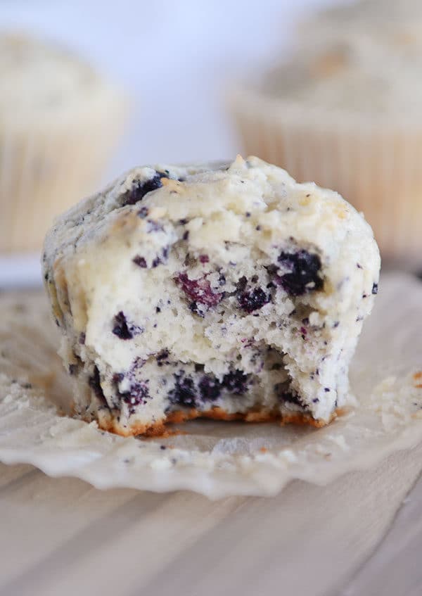 An unwrapped blueberry muffin with a bite taken out.