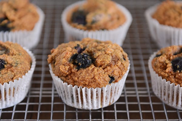 Blueberry pumpkin muffins in white liners on a cooling rack. 