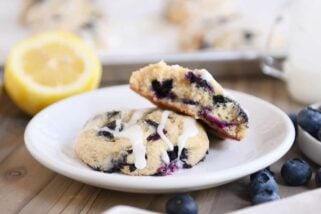 Blueberry muffin cookies on white plate with top cookie broken in half.