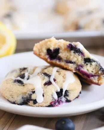 Blueberry muffin cookies on white plate with top cookie broken in half.