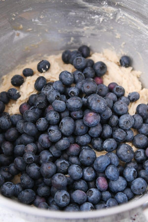 Blueberries added to cookie batter in stainless bowl.