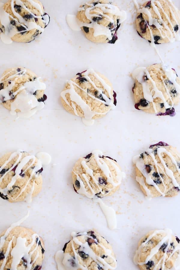 Top down view of several blueberry muffin cookies on baking sheet with lemon glaze.