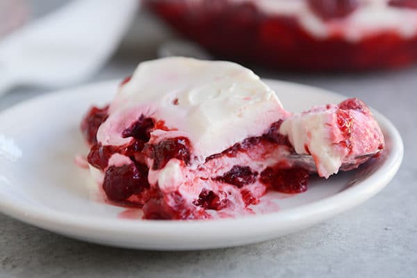 A layered raspberry Jello dessert on a white plate. 