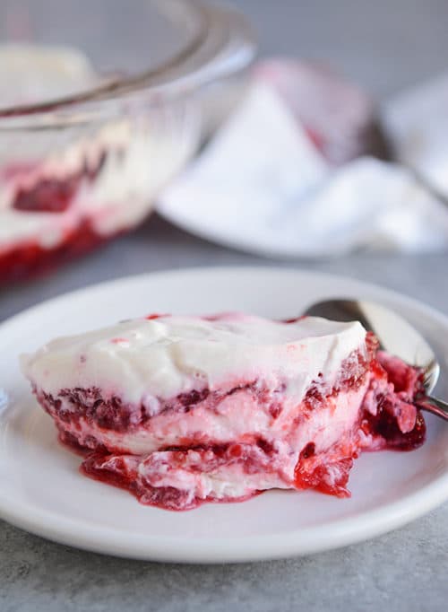 A helping of raspberry layered Jello dessert on a white plate.