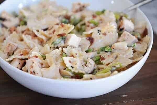 A white bowl full of creamy bowtie pasta with chicken and asparagus. 
