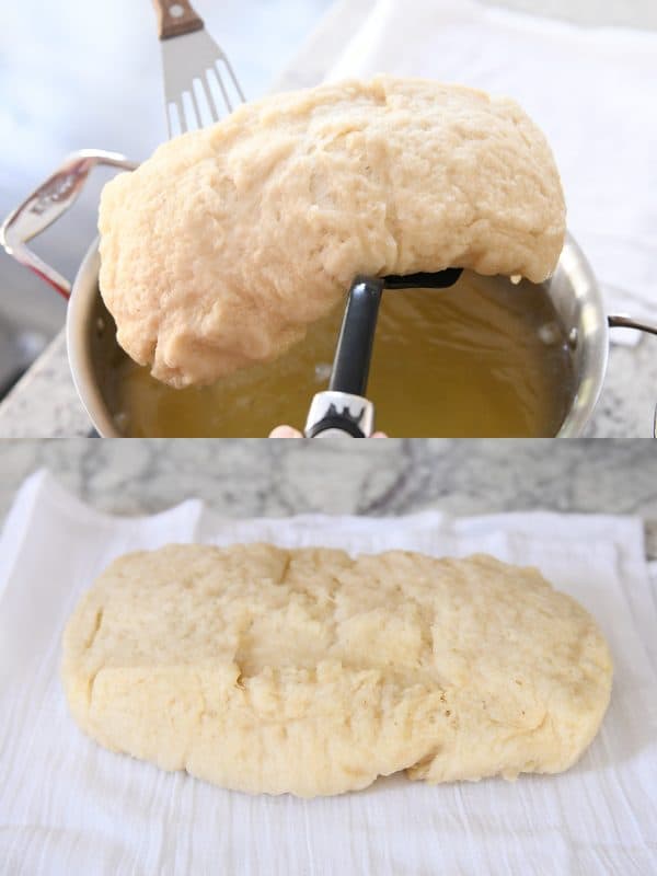 A spatula lifting a loaf of bagel bread out of a pot of water.